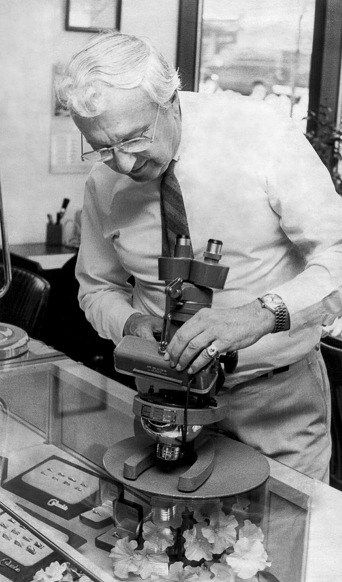 John Saxon examining a piece under a jeweler's microscope